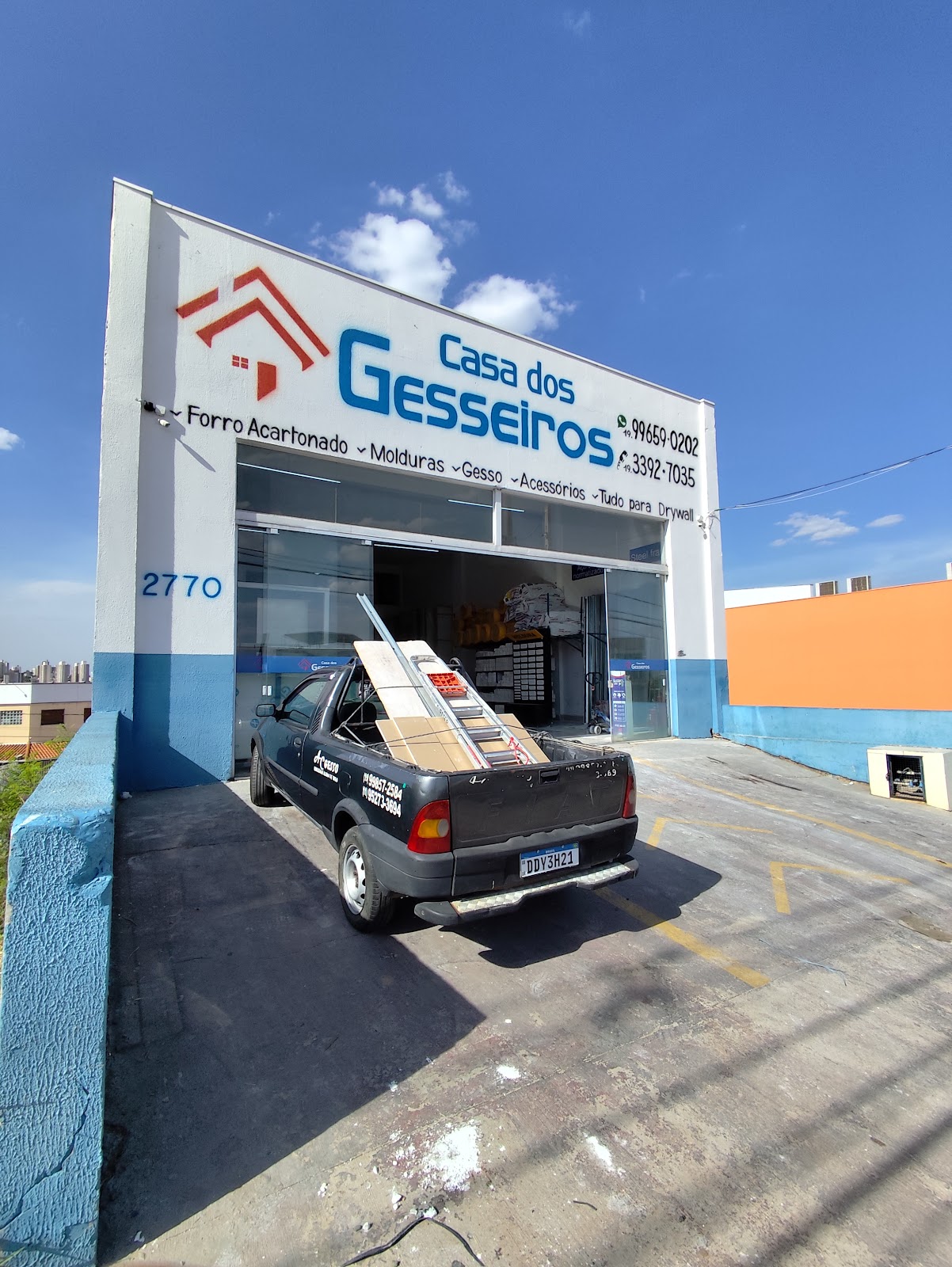 Fachada da Casa dos Gesseiros na Av. Manoel Ruz Peres, 2770, com o letreiro, o número da fachada e uma picape carregada de placas de drywall