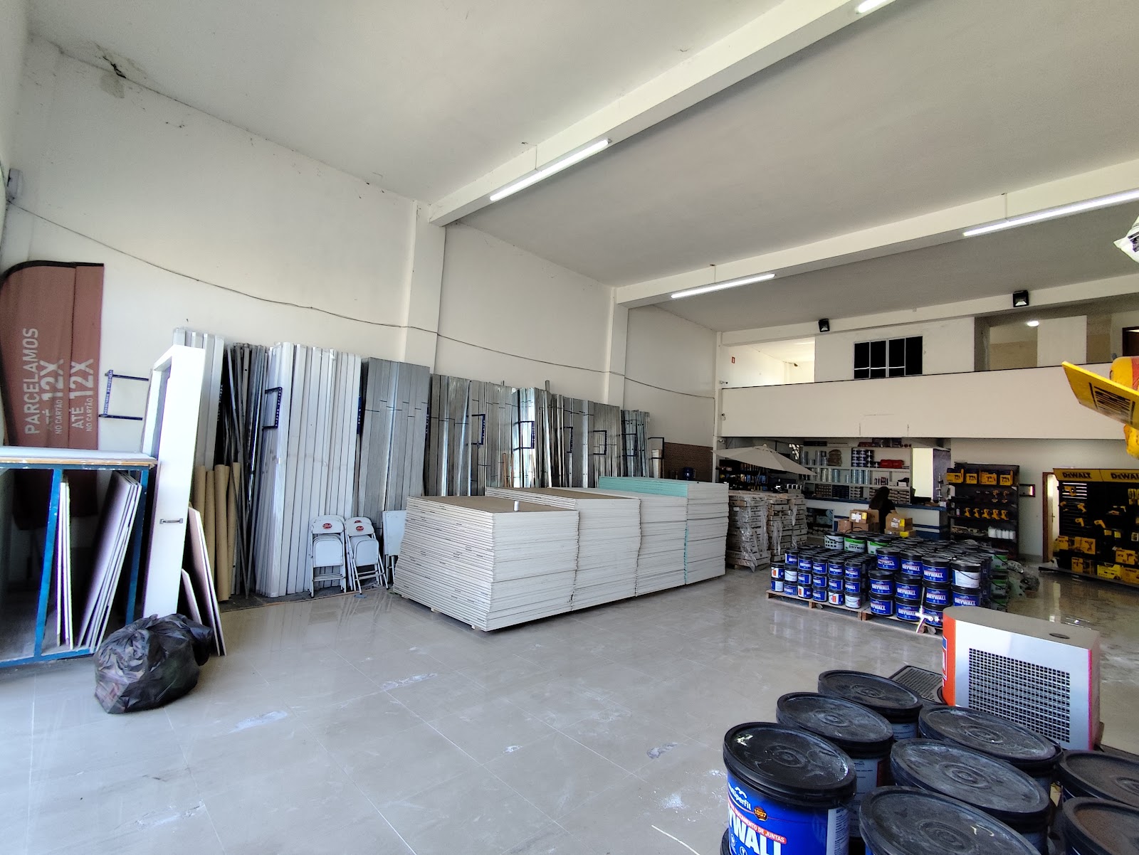 Pilhas de placas de gesso e perfis de aço galvanizado encostados na parede do salão da loja